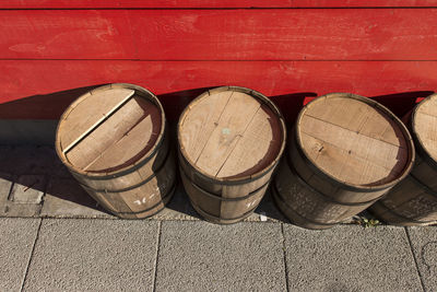 High angle view of wooden barrels on footpath by red wall