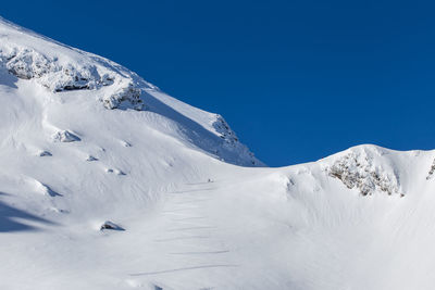 Scenic view of snowcapped mountains against clear blue sky