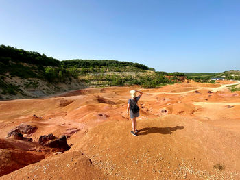 Full length of a girl standing on rock against sky