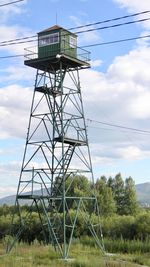 Low angle view of electricity pylon on field against sky