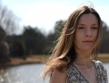 Freckle face, young lady standing outside with wind blowing hair.