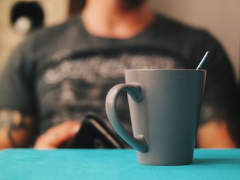 Midsection of man sitting by coffee on table