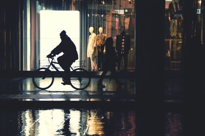 Side view of man riding bicycle on street at night