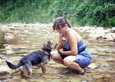 Full length of woman with dog in river against plants