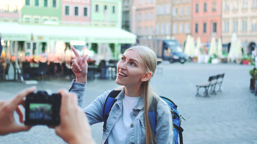 Young woman photographing with mobile phone in city