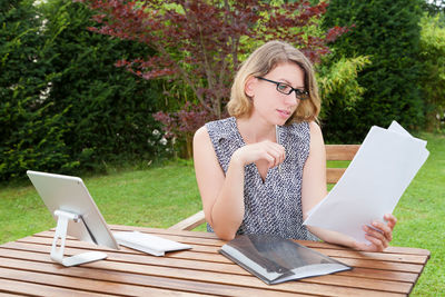 Young woman using mobile phone while sitting on table