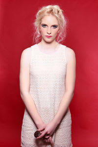 Portrait of smiling young woman against red background