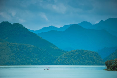 Scenic view of lake by mountains against sky