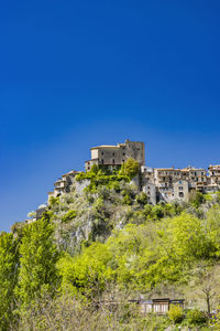 Buildings by sea against clear blue sky