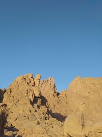 Rock formations on land against clear blue sky