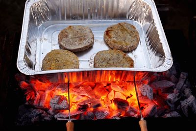 High angle view of patties in container on burning coals