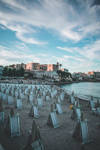 Chairs on beach by buildings against sky in city