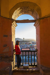 Female tourist looking over potosi rooftops from archway, bolivia