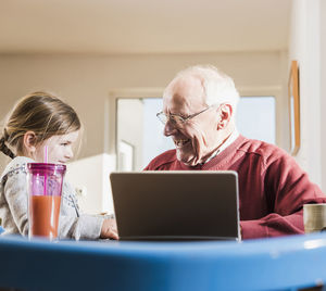 Grandfather and granddaughter using laptop together