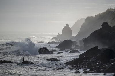 Scenic view of rocks in sea against sky