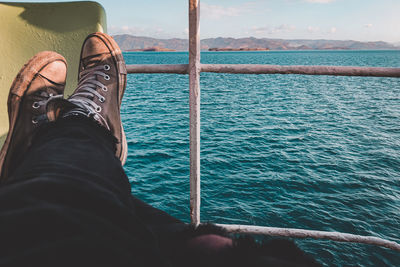 Low section of man relaxing by sea