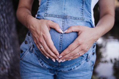 Pregnancy female makes a heart on his pregnant baby