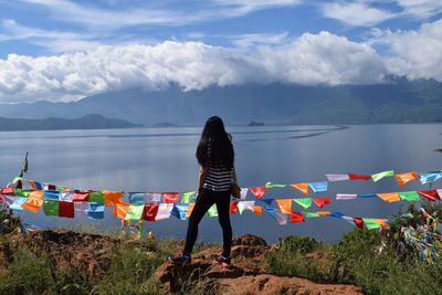 Rear view of young woman standing against lake