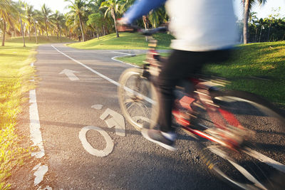 Blurred motion of man riding bicycle on road