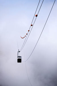 Low angle view of overhead cable car during foggy weather