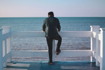 Rear view of man looking at sea against sky