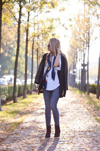 Portrait of woman walking on footpath in park