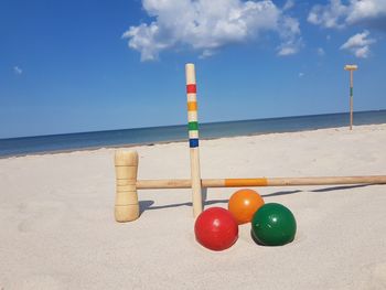 Multi colored bals on beach against sky