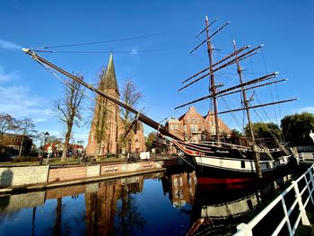 Sailboats moored on canal against sky