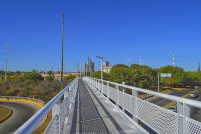 Road by trees against clear blue sky