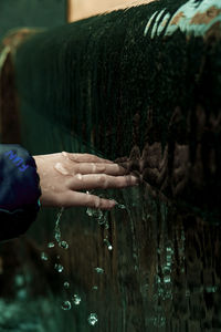 Midsection of man holding leaf in water