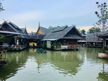 Houses by river and buildings against sky
