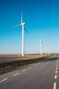 Wind turbines on landscape against clear blue sky