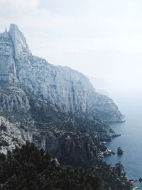 Scenic view of sea by mountain against sky