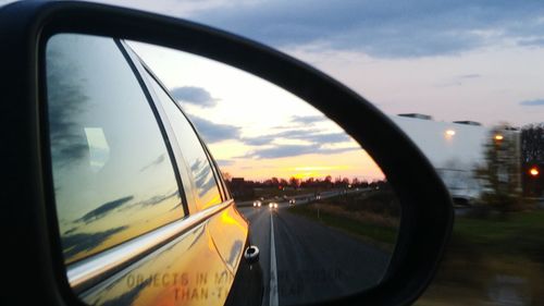 Close-up of side-view mirror against sky