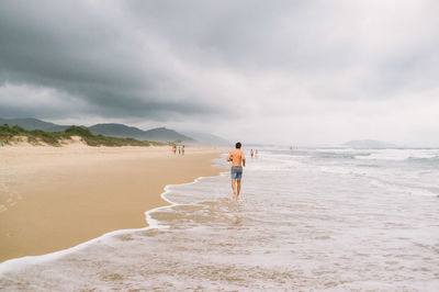 Full length of woman walking on beach against sky