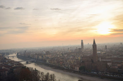 River amidst buildings against sky during sunset