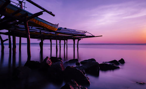 Traditional windmill on beach against sky during sunset