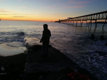 Silhouette man standing on beach during sunset