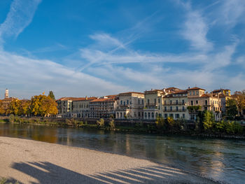 Buildings by river against sky
