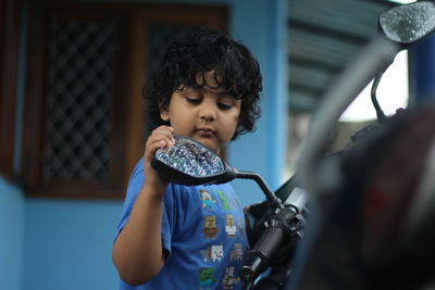 Low angle view of boy standing by motorcycle