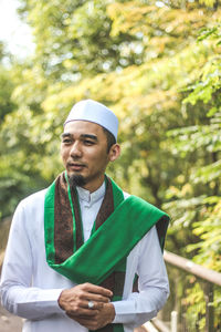 Young man standing against trees