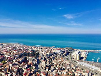 High angle view of townscape by sea against blue sky