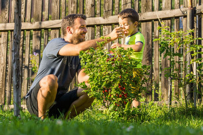 Man feeding food to son in yard