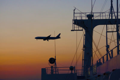 Low angle view of airplane flying against sky during sunset