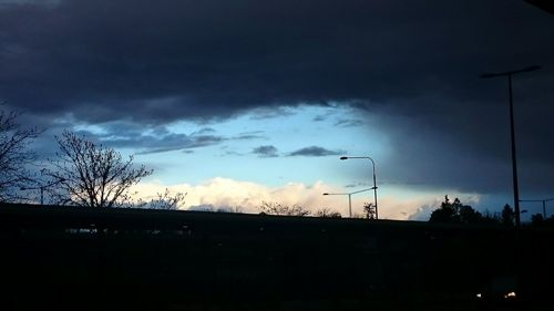 Low angle view of silhouette trees against cloudy sky