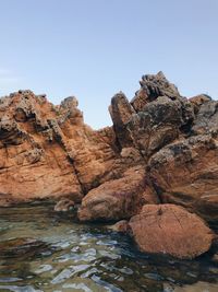 Rock formations in water against clear sky