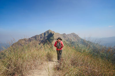 Rear view of man standing on mountain against sky