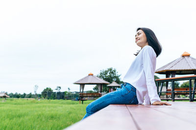 Side view of young woman on field against clear sky