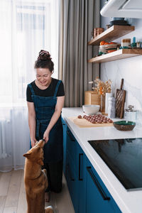 Funny woman cooking meatballs and treating her dog to a piece of minced meat. cooking at home