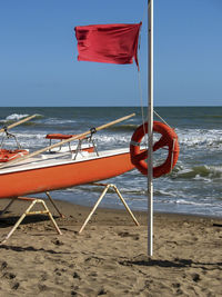 Rescue boat with red danger flag on an italian beach.